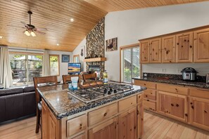 A spacious kitchen with wooden cabinets, a granite countertop, and a central island with seating. - Big Bear House | Hot Tub | Summit Shuttle | Max 11 (Big Bear Lake)