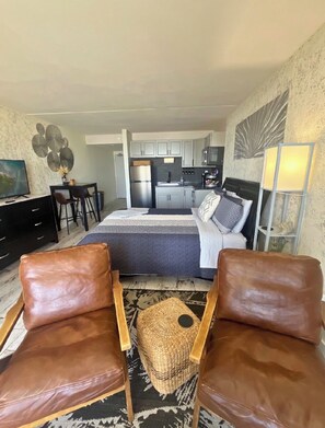 A compact hotel room with a bed, a desk, a kitchenette, and two leather chairs. - Oceanfront Coastal Comfort - Unique and Beautiful
Sand Dunes Resort (Myrtle Beach)