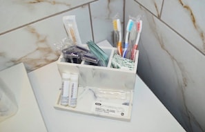 A bathroom with a marble wall, a white sink, and a toothbrush holder containing toothbrushes and dental floss. - Oceanfront Coastal Comfort - Unique and Beautiful
Sand Dunes Resort (Myrtle Beach)