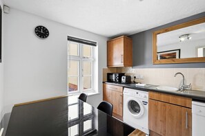 Een kleine keuken met een wasmachine, een magnetron en een spoelbak.
