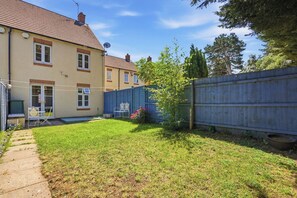 A residential backyard with a lawn, a wooden fence, and a house with a satellite dish. - Modern 3BR Retreat|Garden & Parking (Solihull)