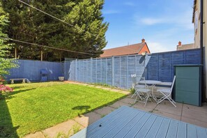 A backyard with a fenced area, a table and chairs, and a green door. - Modern 3BR Retreat|Garden & Parking (Solihull)