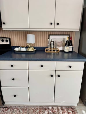 A kitchen with white cabinets, a blue countertop, a coffee maker, a kettle, and two bottles of wine. - 3 bed, 2 bath canal front house with boat lift and pool (Port Charlotte)
