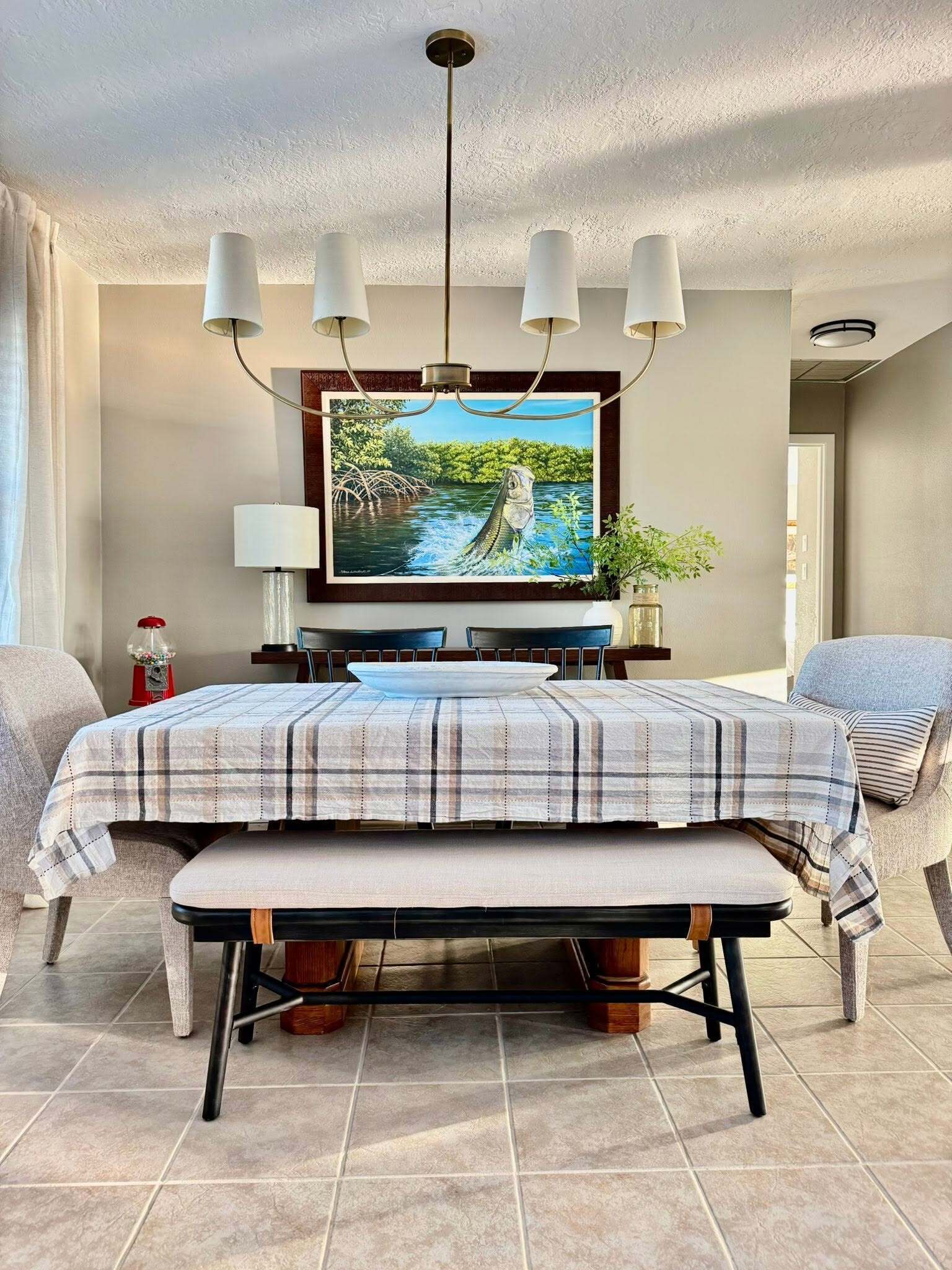 A dining area with a table set for two, a television mounted on the wall, and a ceiling light fixture.