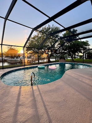 An indoor swimming pool with a view of the sunset, surrounded by trees and a clear sky. - 3 bed, 2 bath canal front house with boat lift and pool (Port Charlotte)