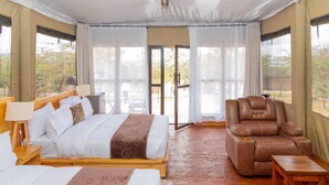 Un dormitorio con cama, mesitas de noche, una silla y vistas al exterior.
