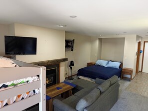 A bedroom with a bed, a television, a fireplace, a sofa, and a small table.