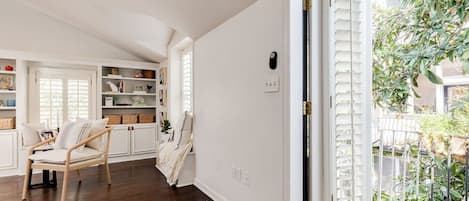 Una habitación con piso de madera, una puerta blanca con marco negro y una pared blanca con un pequeño objeto negro.