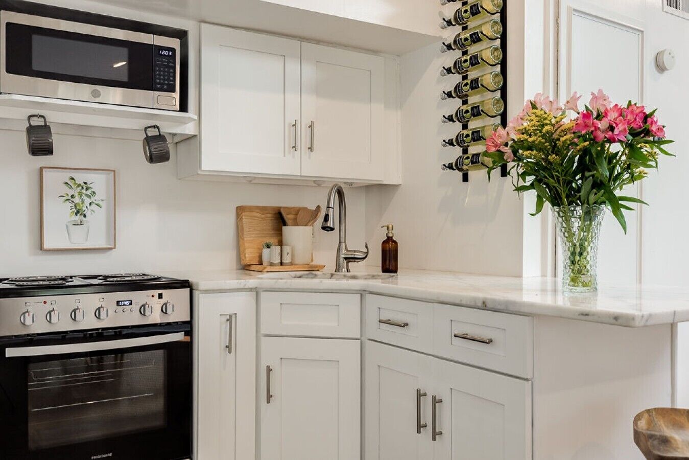 A modern kitchen with white cabinetry, a built-in microwave, a gas stove, and a wine rack.