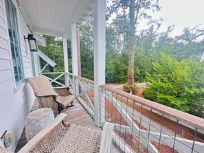 Eine überdachte Veranda mit Korbmöbeln und Blick auf ein bewaldetes Gebiet.