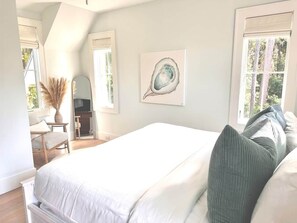 A bedroom with a large bed, a chair, a desk, and a window. - Corley Cottage - 2-bdr, Includes 2 Bikes & Moke/Golf Cart (Bluffton)