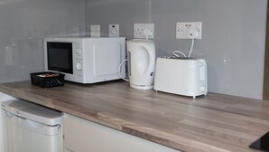 Eine Küche mit Mikrowelle, Wasserkocher und Toaster auf einer Holzauslage.