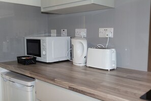 Eine Küche mit Mikrowelle, Wasserkocher und Toaster auf einer Holzauslage.