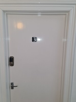 Una porta bianca con un adesivo con il numero 3, una serratura a tastierino e una maniglia.