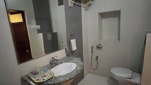 Een badkamer met een wastafel, spiegel, toilet en douche.