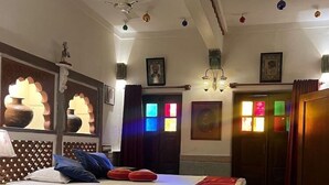 Hotelkamer met een bed, nachtkastje, lamp, wandplank met decoratieve spullen en een vloer met patroon.
