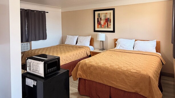 Ein Hotelzimmer mit zwei Betten, einer Deckenlampe, einem gerahmten Bild und einem Papierkorb.