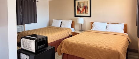 A hotel room with two beds, a ceiling light, a framed picture, and a trash bin.