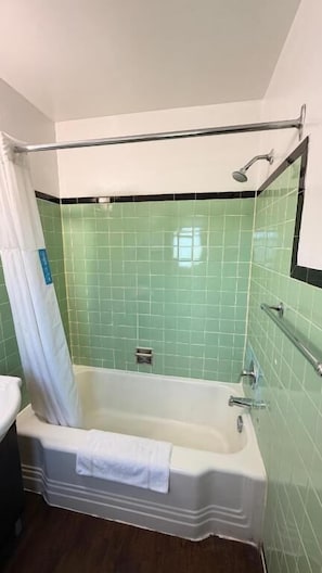A bathroom with a bathtub, a shower, and a handrail. - Queen's Motel Blenheim Near Lake Erie ON (Blenheim)
