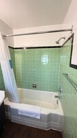 Baño con bañera, ducha y barra de apoyo.