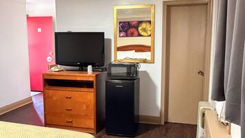 Ein Hotelzimmer mit einem Bett, einem Holzschrank, einem Fernseher, einer Mikrowelle und einer Tür.