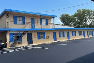 Un motel con estructura de dos pisos, estacionamiento y fachada azul.