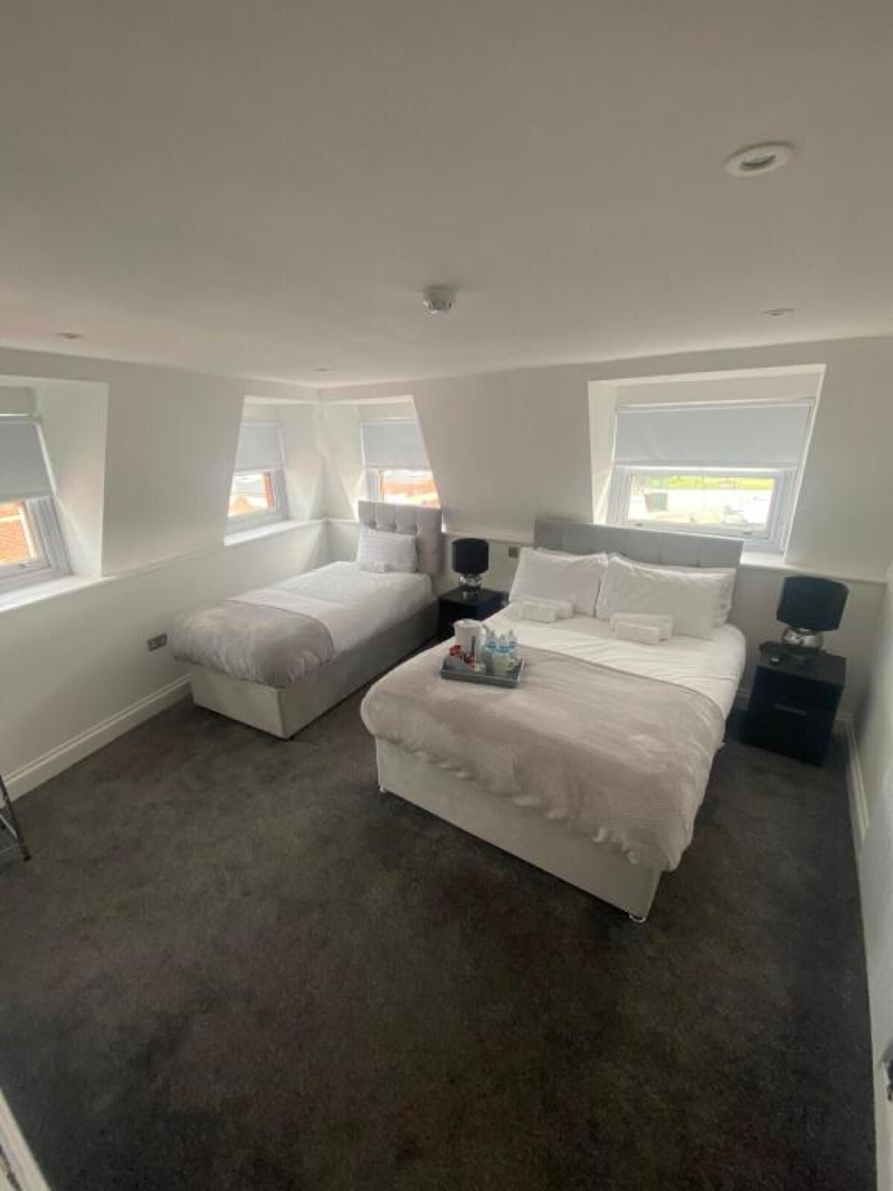 A bedroom with two beds, a small table, and a nightstand.