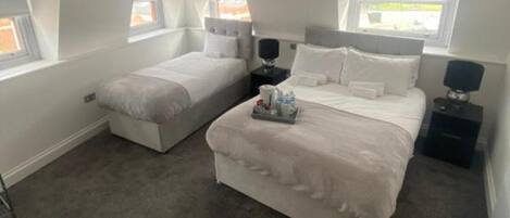 A bedroom with two beds, a small table, and a nightstand.