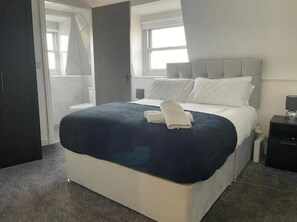 A hotel room with a bed, a nightstand, a window, and a door. - OYO The Royal Crest Hotel & Bar (Liverpool)