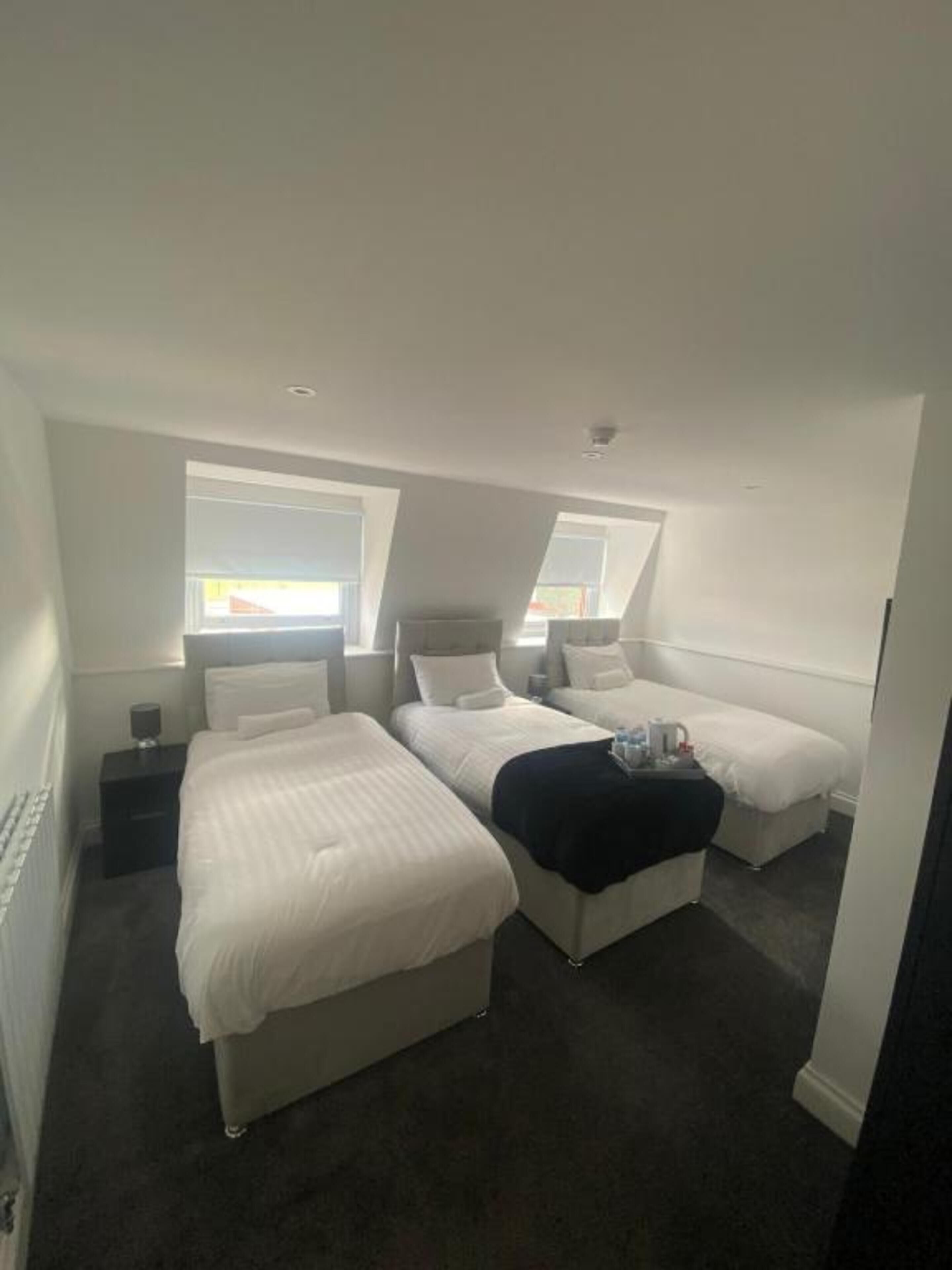 A compact room with two beds, a small bedside table, and a window.