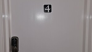 Eine weiße Tür mit der Nummer 4, einem Zahlenschloss und einer kleinen Steckdose.
