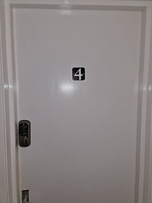 A white door with a number 4 sign, a keypad lock, and a small electrical outlet. - Studio Flat near University of Aberdeen (Aberdeen)