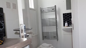 Ein Badezimmer mit Toilette, Handtuchhalter, Waschbecken mit Seifenspender und einem Fenster.