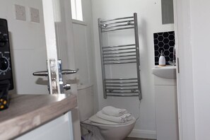 A bathroom with a toilet, a towel rack, a sink with a soap dispenser, and a window. - Studio Flat near University of Aberdeen (Aberdeen)