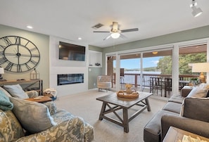 A spacious living room with a large clock, a ceiling fan, and a view to the outside. - 2-bedroom condo in perfect Hot Springs with cool AC (Hot Springs)