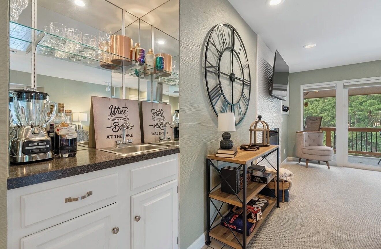 A kitchen with a large mirror, wine bottles, and a sign that reads 'Wine Always Tastes Better at the Table.'