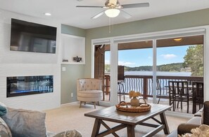 A living room with a fireplace, a television, and a view of a lake. - 2-bedroom condo in perfect Hot Springs with cool AC (Hot Springs)
