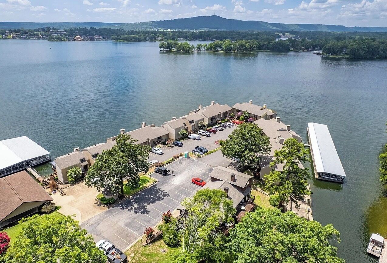 A lakeside property with a parking lot, buildings, and a dock.