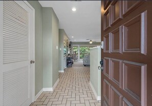 A hallway with a herringbone patterned floor, a door with a decorative panel, and a ceiling fan. - 2-bedroom condo in perfect Hot Springs with cool AC (Hot Springs)