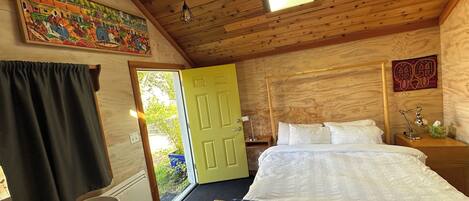A room with a bed, a desk, a chair, a window, and a door.