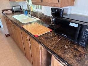 A kitchen with a granite countertop, a wooden cutting board, a coffee maker, and a microwave. - Cozy 2-bedroom cabin Wofford Heights, with hot tub/AC/sauna (Wofford Heights)