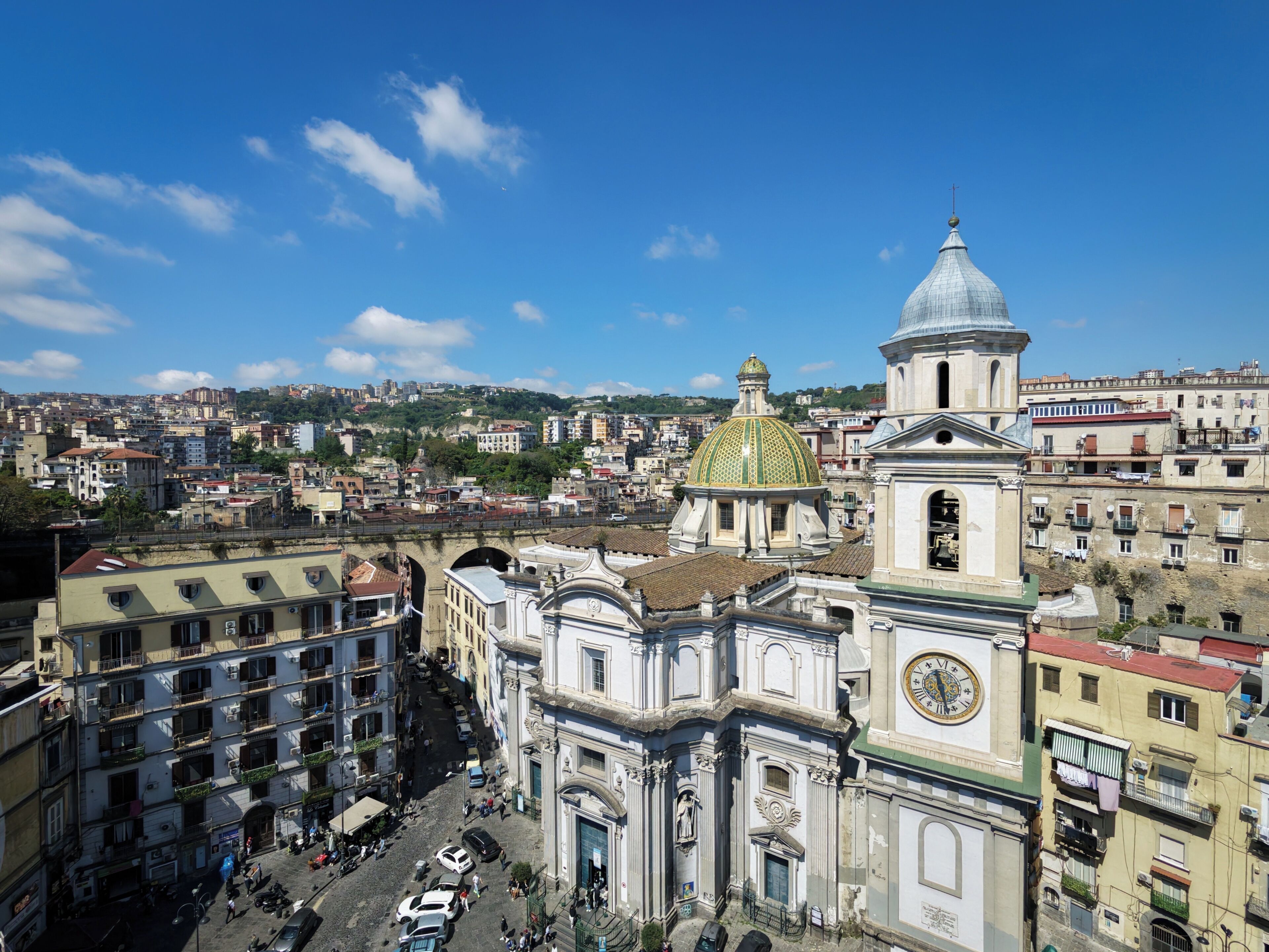 A historic building with a prominent dome and clock tower, surrounded by a densely packed urban area.