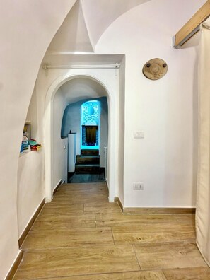 A hallway with wooden flooring, white walls, and a blue-lit staircase leading to a room. - Your home in the heart of the Rione Sanità neighborhood. Authenticity, relaxation, and charm. (Napoli)