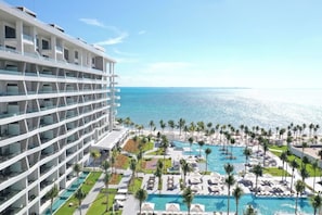 A hotel with multiple floors, a pool area with lounge chairs, and a view of the ocean. - Cozy 1-bedroom condo with AC in peaceful Cancun (cancun)