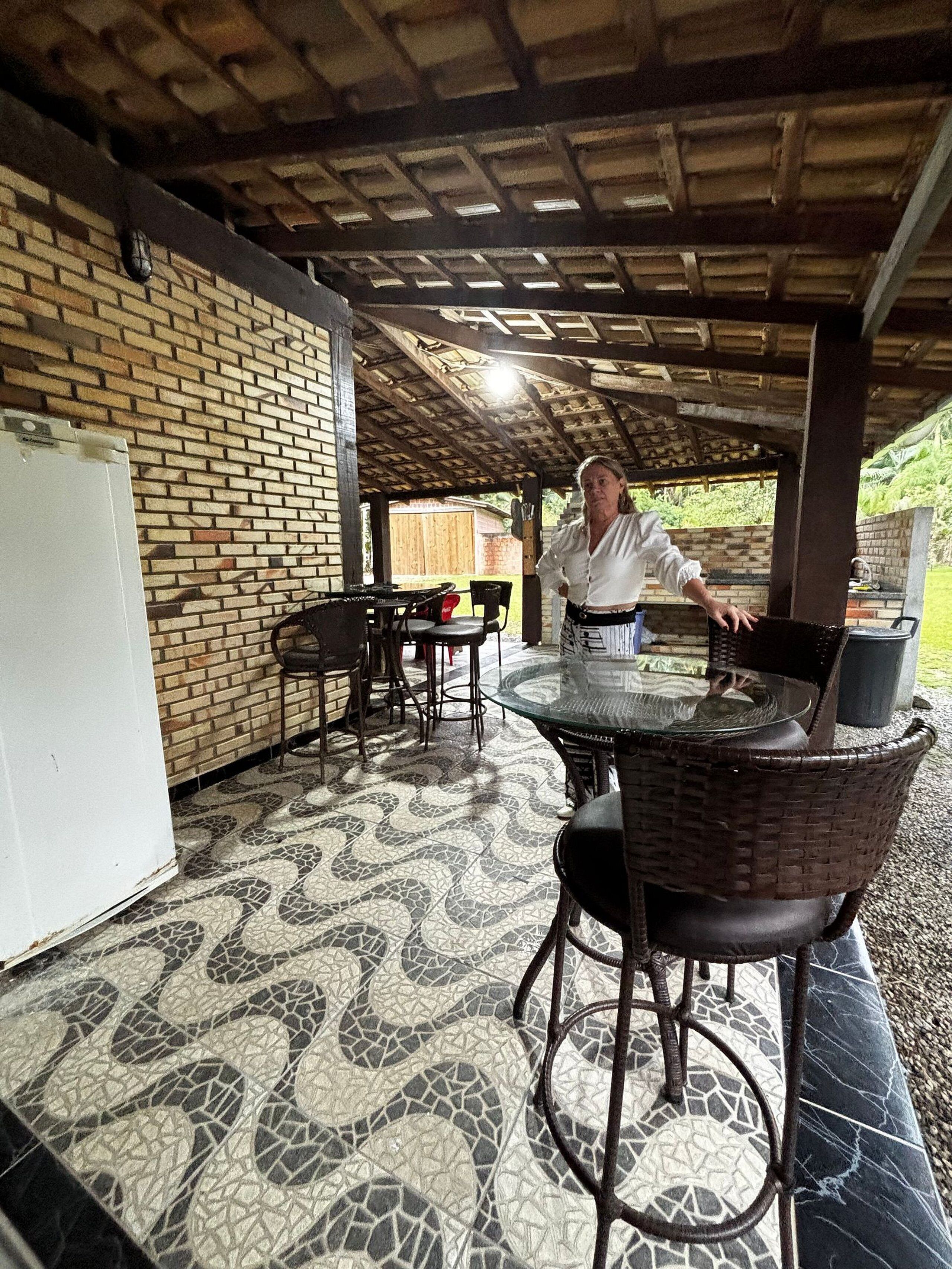 An outdoor patio area with a brick wall, a glass-top table, wicker chairs, and a white refrigerator.