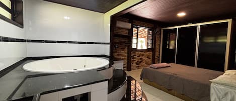 A bathroom with a bathtub, a shower area, and a bed with a towel.