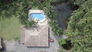An aerial view of a property with a swimming pool, a covered patio, and a vehicle parked nearby. - Casa Luxo Lagoa Piscina Jacuzzi Praia (São Francisco do Sul)