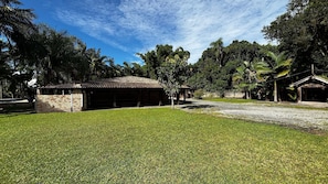 A building with a tiled roof and brick walls, surrounded by a well-maintained lawn and trees. - Casa Luxo Lagoa Piscina Jacuzzi Praia (São Francisco do Sul)
