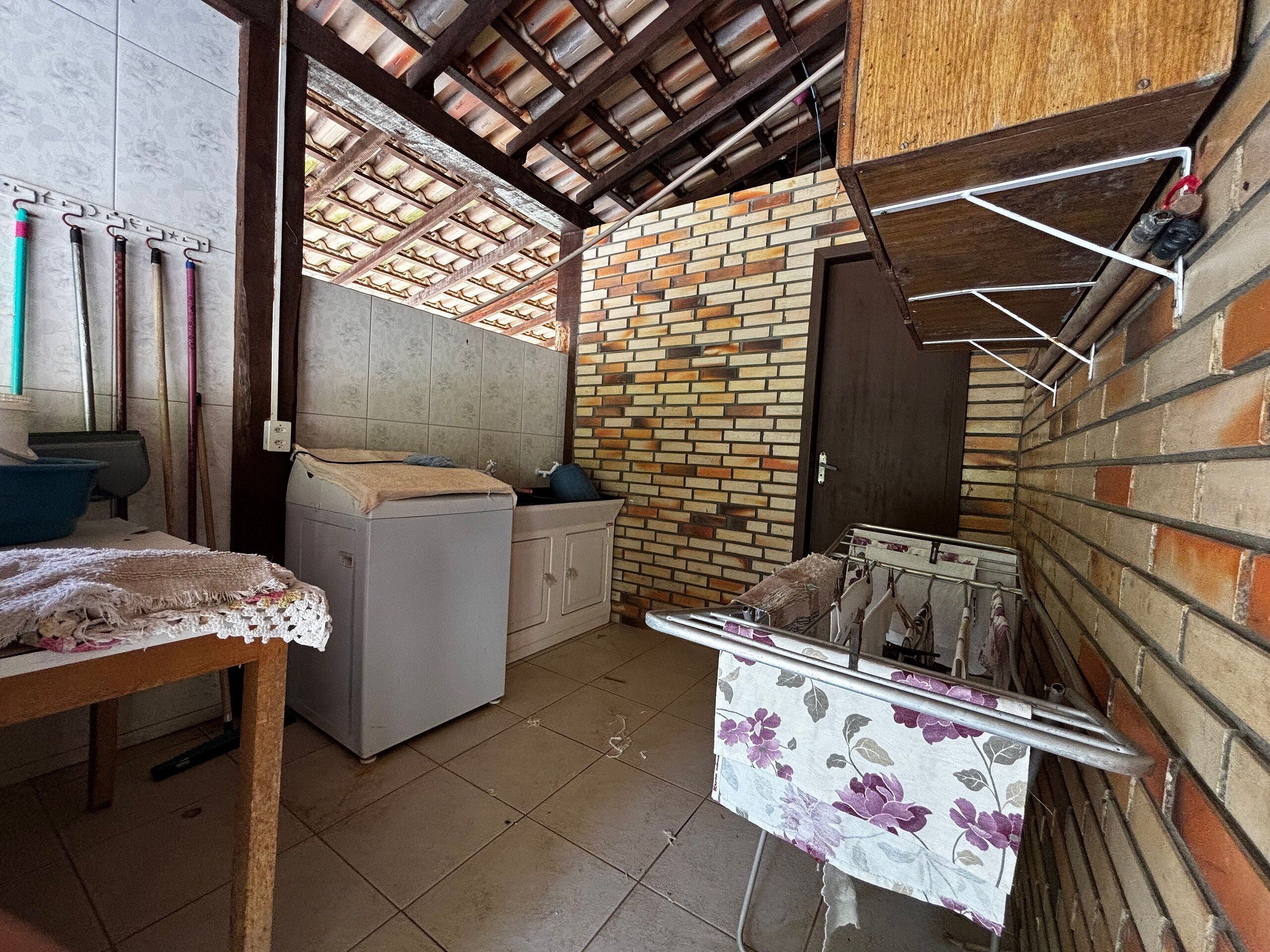 A compact kitchen with a brick wall, a washing machine, and a table with a floral tablecloth.