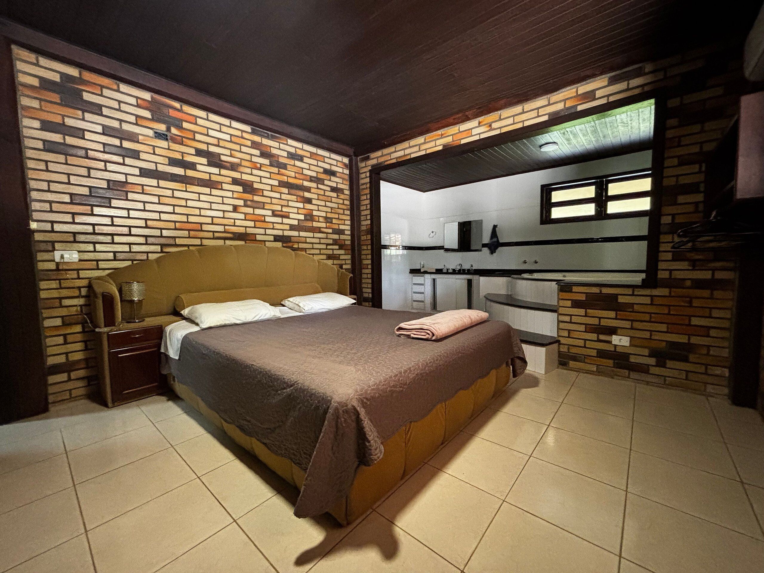 A bedroom with a bed, a nightstand, a mirror, and a built-in kitchen area.